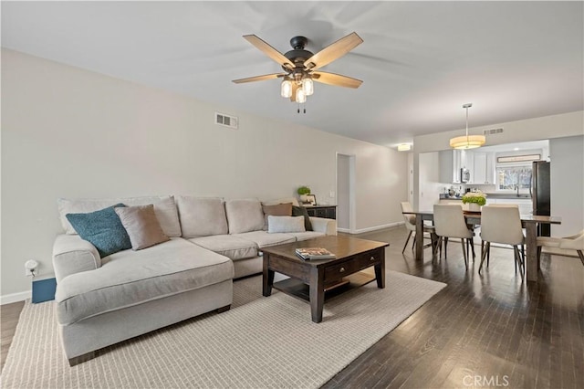 living room featuring visible vents, ceiling fan, and dark wood-style flooring