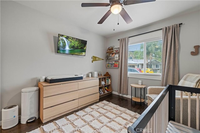 bedroom with dark wood-type flooring, a ceiling fan, and baseboards