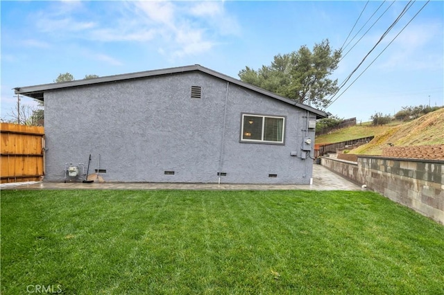 rear view of property featuring crawl space, stucco siding, a yard, and fence