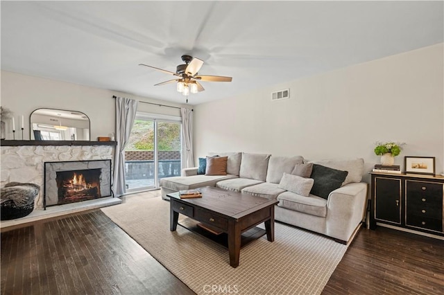 living room with visible vents, a fireplace, a ceiling fan, and hardwood / wood-style flooring