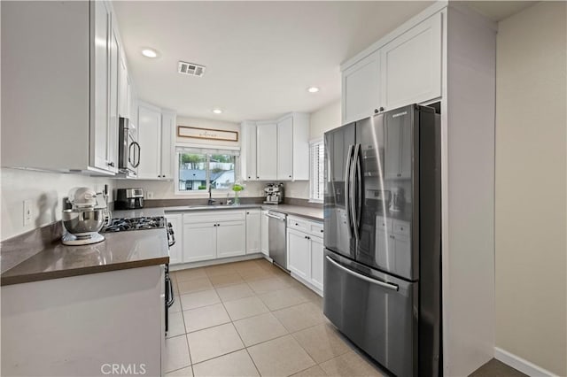 kitchen with light tile patterned floors, visible vents, a sink, white cabinets, and appliances with stainless steel finishes