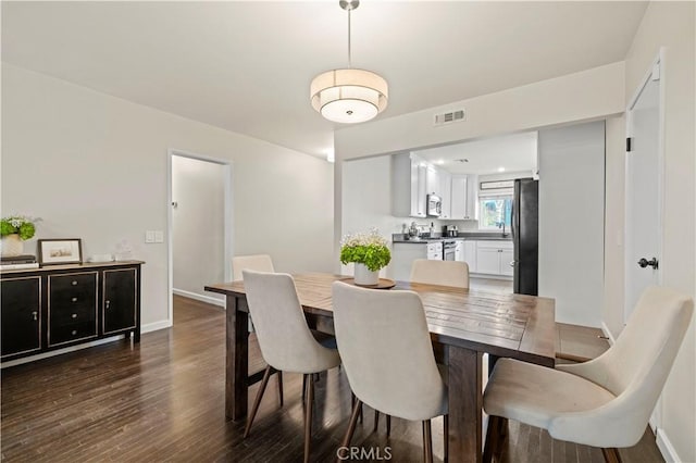 dining area featuring dark wood-style floors, visible vents, and baseboards