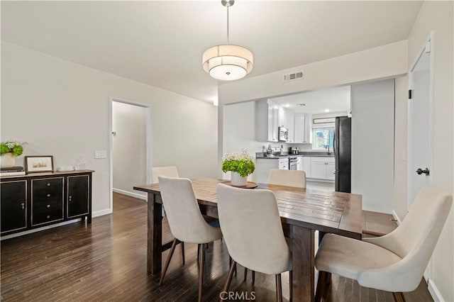 dining space featuring dark wood-style floors, visible vents, and baseboards