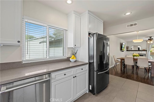 kitchen featuring visible vents, white cabinets, freestanding refrigerator, and stainless steel dishwasher