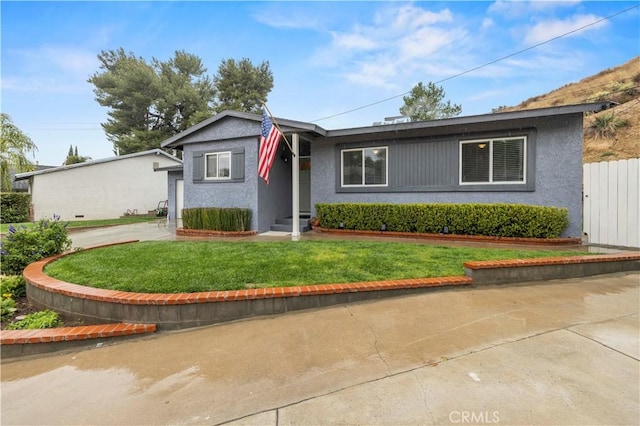 ranch-style home with a front yard, concrete driveway, fence, and stucco siding