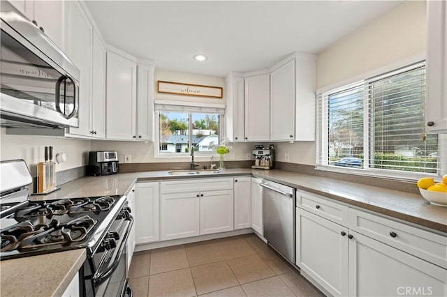 kitchen featuring a sink, recessed lighting, appliances with stainless steel finishes, white cabinets, and light tile patterned flooring