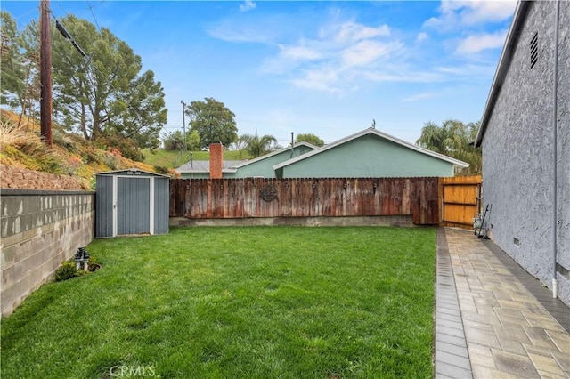 view of yard featuring a storage shed, a fenced backyard, and an outbuilding