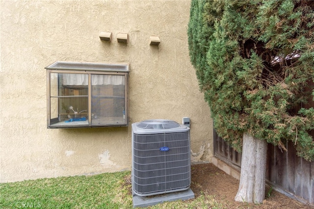 details featuring central AC unit, fence, and stucco siding