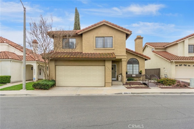 mediterranean / spanish house featuring stucco siding, a garage, concrete driveway, and a tiled roof