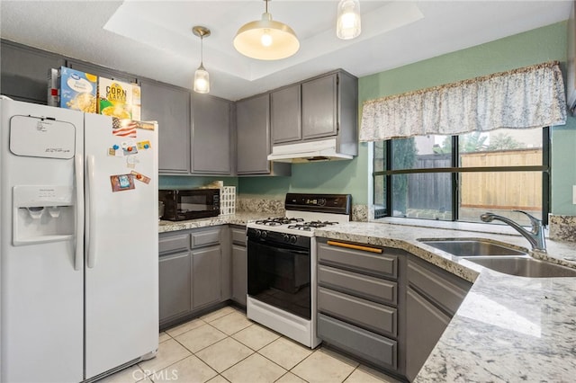 kitchen with gray cabinetry, under cabinet range hood, white fridge with ice dispenser, range with gas cooktop, and a raised ceiling