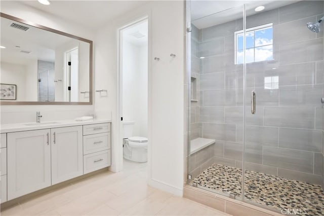 full bathroom with vanity, toilet, visible vents, and a stall shower