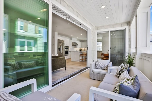 living area featuring recessed lighting, wooden ceiling, and a decorative wall