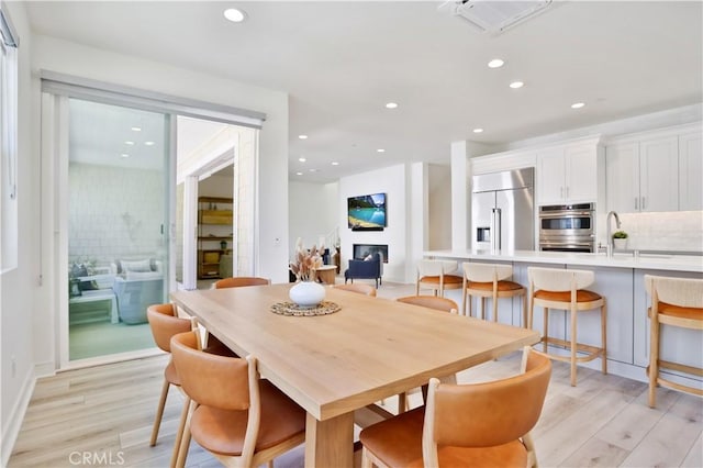 dining room featuring recessed lighting, visible vents, light wood-style floors, and a fireplace