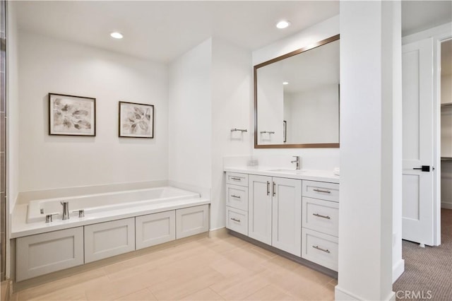 bathroom with a bath, recessed lighting, and vanity