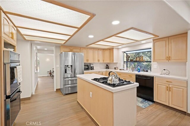 kitchen with a kitchen island, stainless steel appliances, and light brown cabinetry