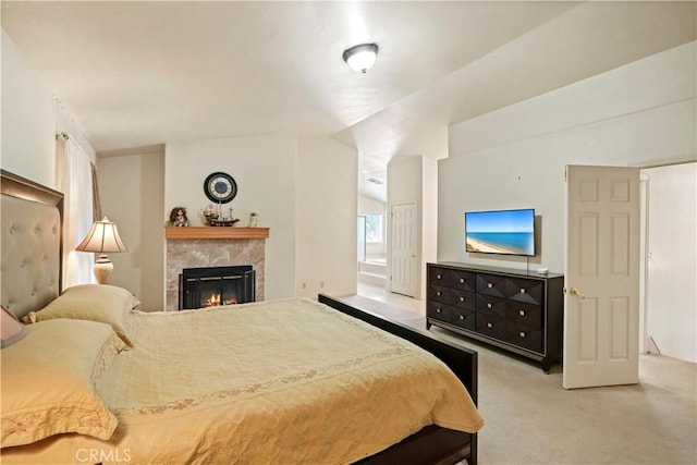 bedroom with lofted ceiling, ensuite bath, carpet, and a tile fireplace