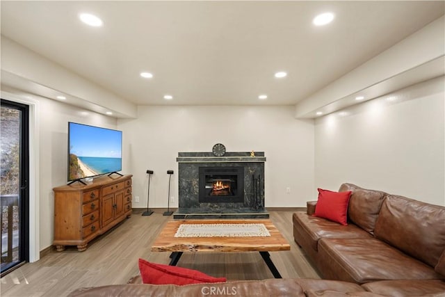 living room featuring a premium fireplace, recessed lighting, and light wood-style floors