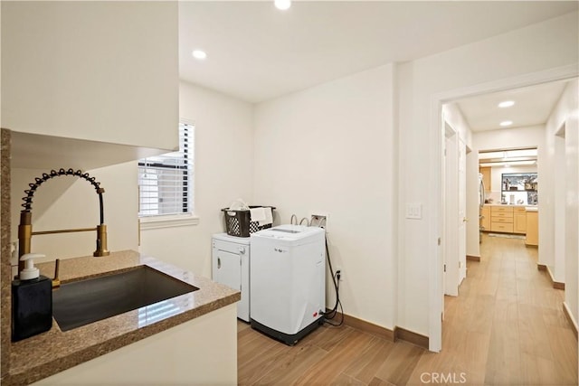 washroom featuring light wood finished floors, baseboards, independent washer and dryer, a sink, and recessed lighting