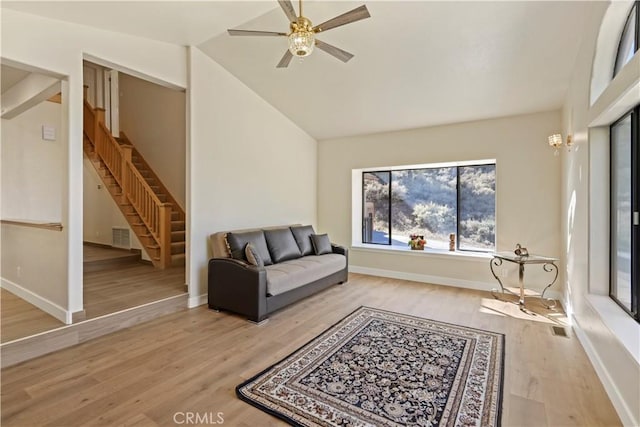 living area featuring wood finished floors, visible vents, baseboards, vaulted ceiling, and stairway