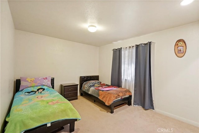 bedroom with baseboards and light colored carpet