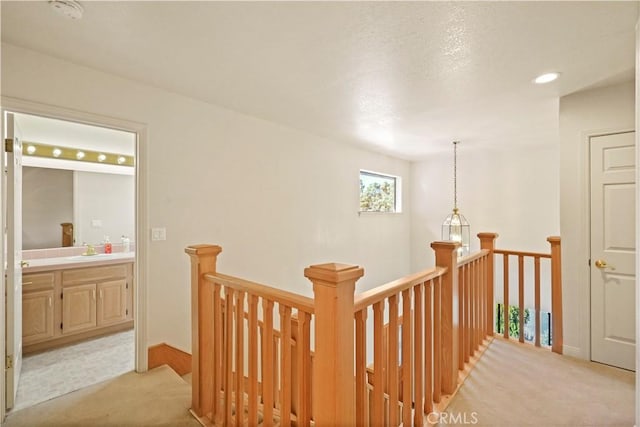 corridor with recessed lighting, a sink, an upstairs landing, and light colored carpet