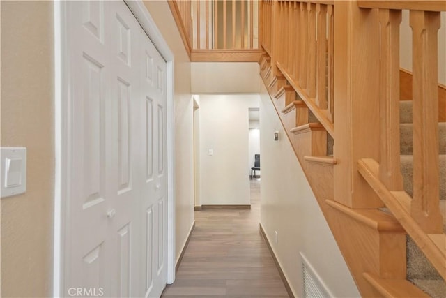 hallway featuring visible vents, stairway, baseboards, and wood finished floors