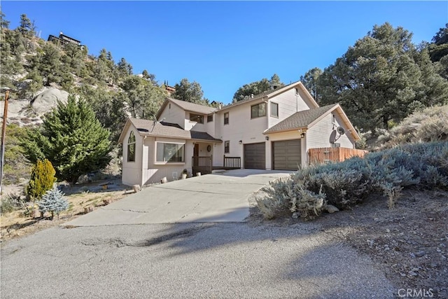 traditional home with driveway, an attached garage, and fence