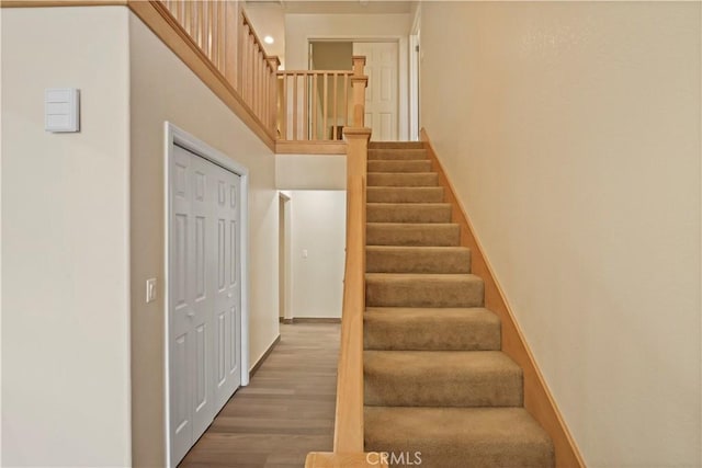 staircase with baseboards, a high ceiling, and wood finished floors