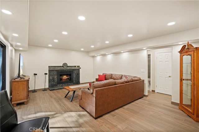 living area featuring baseboards, light wood finished floors, a fireplace, and recessed lighting