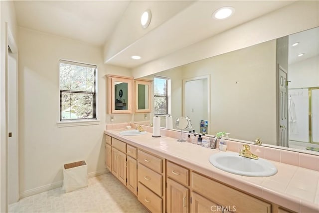 full bathroom featuring double vanity, a wealth of natural light, and a sink