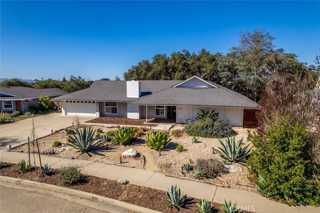 ranch-style home featuring driveway, a chimney, and an attached garage