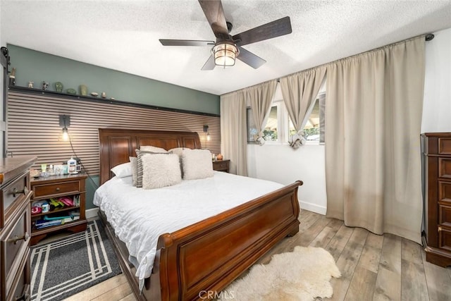 bedroom featuring a textured ceiling, ceiling fan, and light wood finished floors