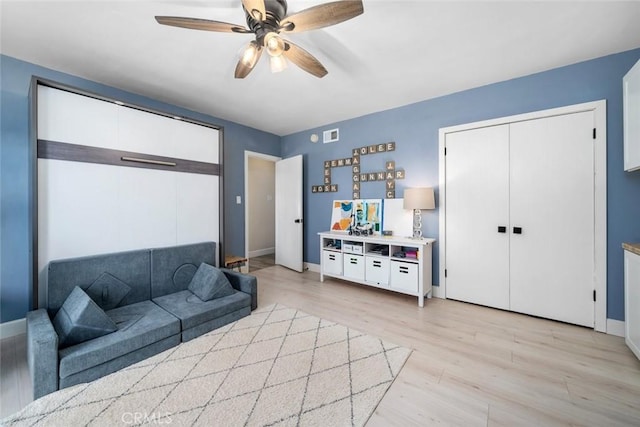 living area featuring ceiling fan, light wood finished floors, and baseboards