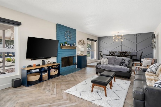 living area featuring baseboards, a fireplace, a chandelier, and a textured ceiling