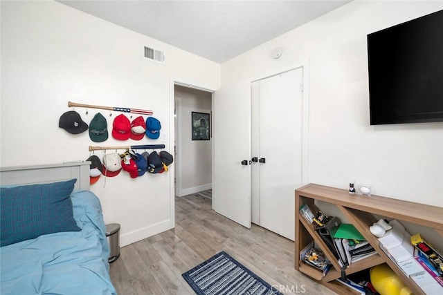 interior space featuring baseboards, a textured ceiling, visible vents, and wood finished floors