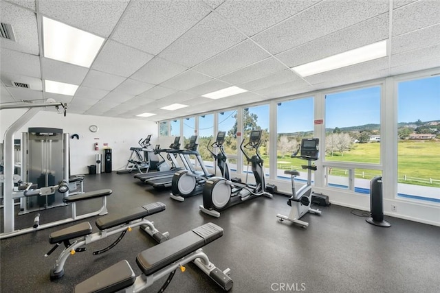 workout area featuring visible vents, a paneled ceiling, and baseboards