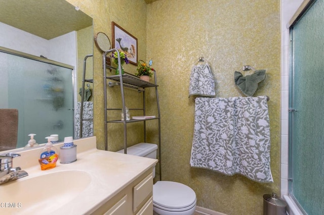 bathroom with toilet, vanity, and a shower with shower door