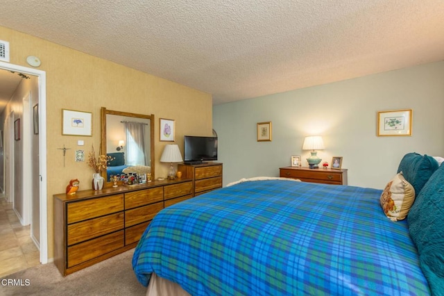 bedroom featuring light carpet, visible vents, and a textured ceiling