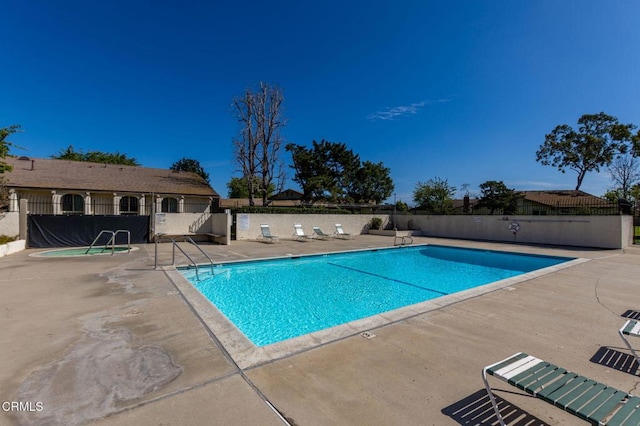 community pool with a patio and fence