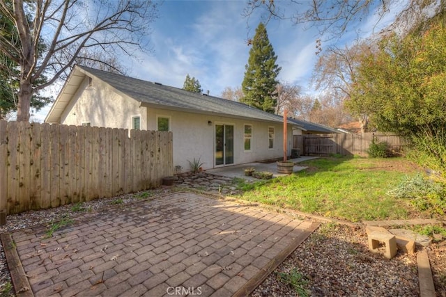 rear view of property featuring a patio area, a yard, a fenced backyard, and stucco siding