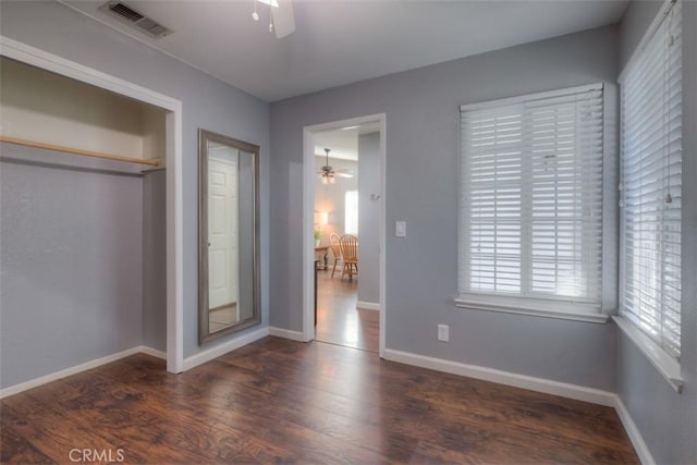 unfurnished bedroom featuring a closet, visible vents, baseboards, and wood finished floors