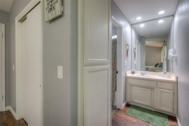 bathroom with recessed lighting, wood finished floors, vanity, baseboards, and ensuite bath