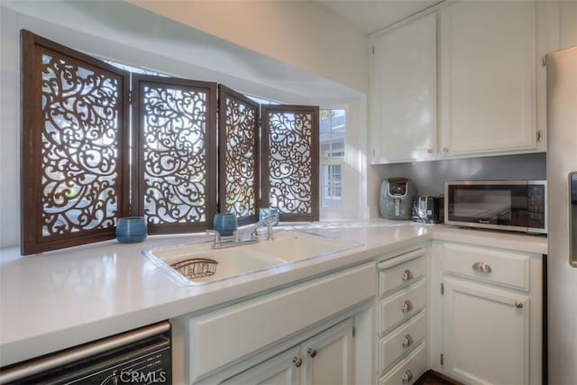 kitchen featuring light countertops, stainless steel microwave, a sink, and dishwasher