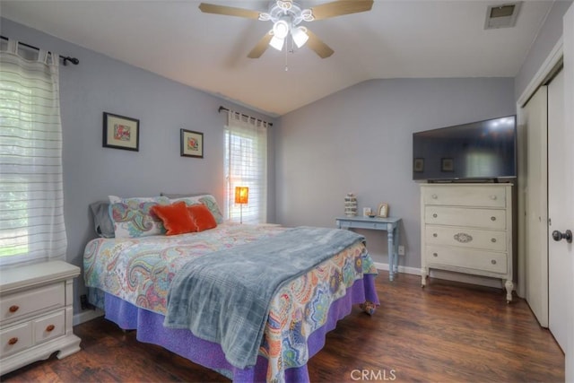 bedroom with a closet, visible vents, dark wood-type flooring, vaulted ceiling, and ceiling fan