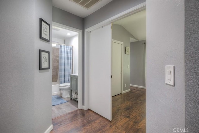 corridor featuring baseboards, visible vents, and wood finished floors