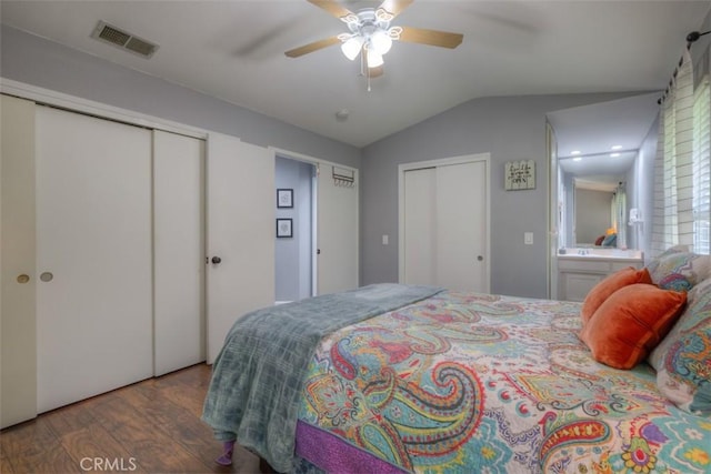 bedroom featuring multiple closets, visible vents, a ceiling fan, vaulted ceiling, and wood finished floors