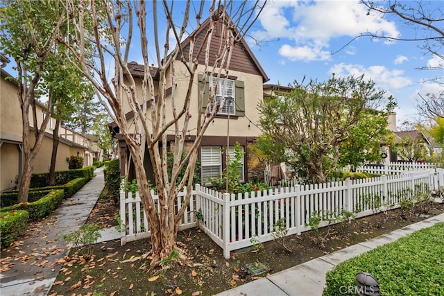 view of side of home featuring a fenced front yard and stucco siding