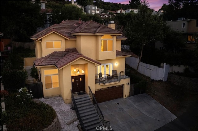 mediterranean / spanish-style home featuring a tile roof, a chimney, stucco siding, fence, and a garage