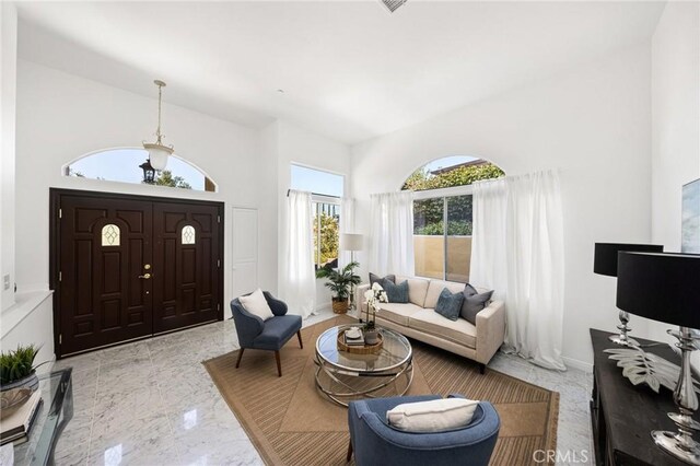 interior space with marble finish floor, a high ceiling, and baseboards