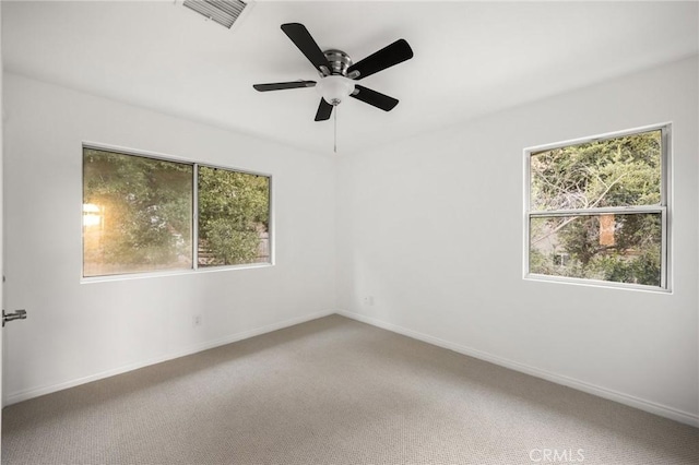 spare room featuring a wealth of natural light, carpet, visible vents, and baseboards